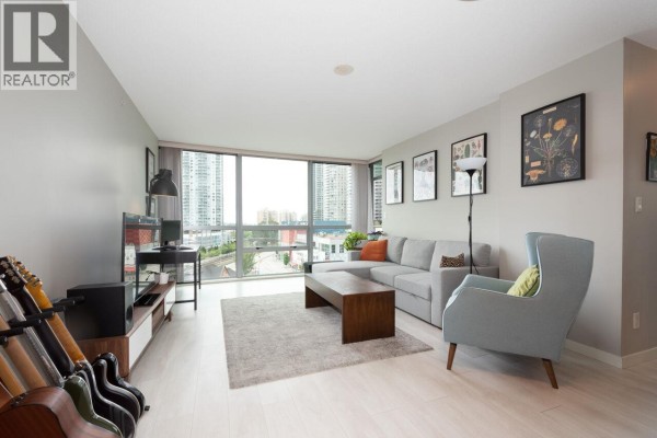 Living room with guitars on a stand, sectional sofa, coffee table, and a large window. - 902 14 Begbie Street, New Westminster