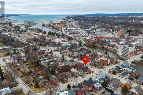 A small bedroom with a single bed, white walls, and a window with a view of buildings. - 902 2nd Avenue W, Owen Sound