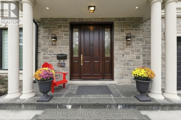 The entrance to a house with a large dark wood door, stone facade, and white pillars. - 902 Parkland Avenue, Mississauga