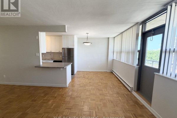 View of an open-concept living and dining area with a breakfast bar and a sliding glass door. - 903 - 1209 Richmond Street, London East
