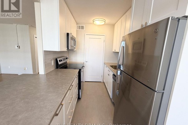 Galley kitchen with white cabinetry, stainless steel appliances, and a gray backsplash. - 903 - 1209 Richmond Street, London East