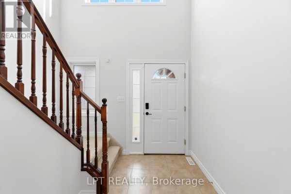 Interior foyer with a white front door, tiled floor, and a carpeted staircase with dark wood railing. - 903 Bradshaw Crescent, London North