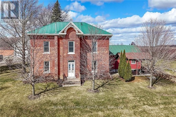 Aerial view of a red brick house with a green roof and surrounding trees. - 903 Concession 13 Townsend Road, Norfolk