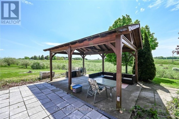 Outdoor covered patio with table, chairs, and grill overlooking a field. - 903 Concession 13 Townsend Road, Norfolk