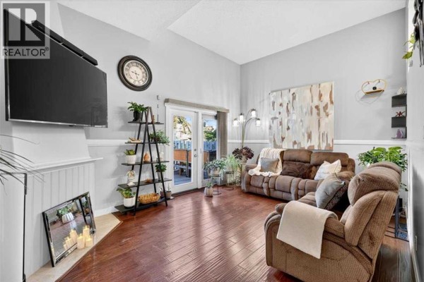 Living room with sofa, TV, fireplace surround, and staircase. - 904, 919 38 Street Ne, Calgary