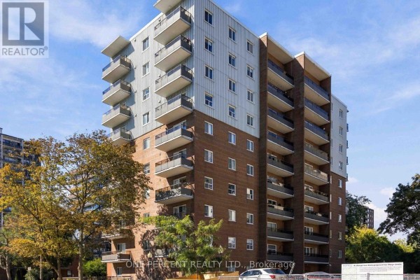 Side view of a multi-story brick apartment building with balconies and trees. - 904 - 15 Elizabeth Street N, Mississauga