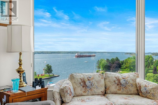 Close-up of a floral sofa and large window with view of a ship on a wide blue river. - 904 - 15 St Andrew Street, Brockville