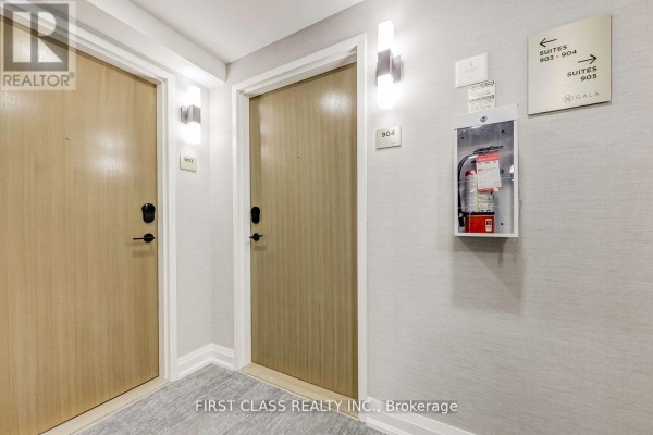 Hallway with two apartment doors, light-colored walls, and a fire alarm box. - 904 - 2369 Danforth Avenue, Toronto