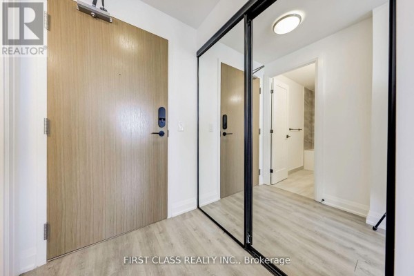 Entryway of the apartment featuring a large mirror and light wood door. - 904 - 2369 Danforth Avenue, Toronto