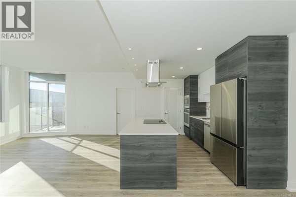 Spacious living area and kitchen with a central island and stainless steel refrigerator. - 904 1628 Store St, Victoria