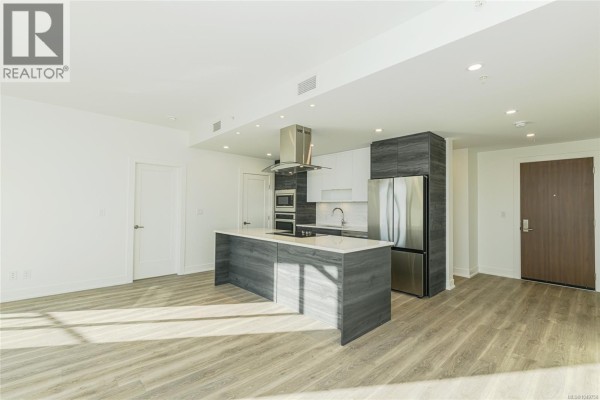 Living area with large windows, a kitchen island with wine cooler, and natural light. - 904 1628 Store St, Victoria