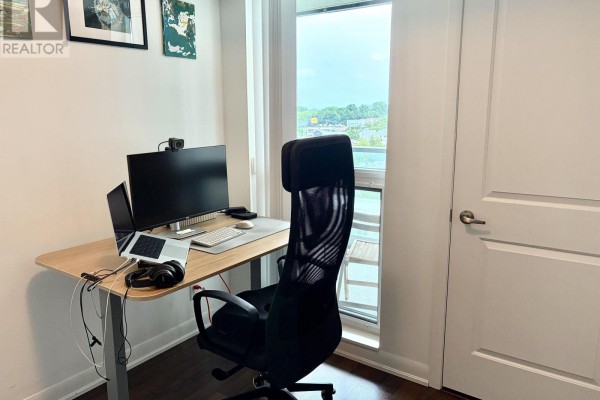 Home office setup with a desk, computer monitors, ergonomic chair, and a window view. - 905 - 17 Anndale Drive, Toronto