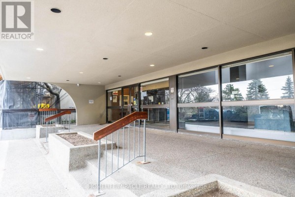 Covered walkway with railings and planters leading to the glass entrance of the building. - 905 - 177 Linus Road, Toronto