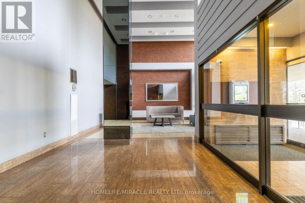 Apartment building lobby with marble floors, brick accent wall, and modern seating area. - 905 - 177 Linus Road, Toronto