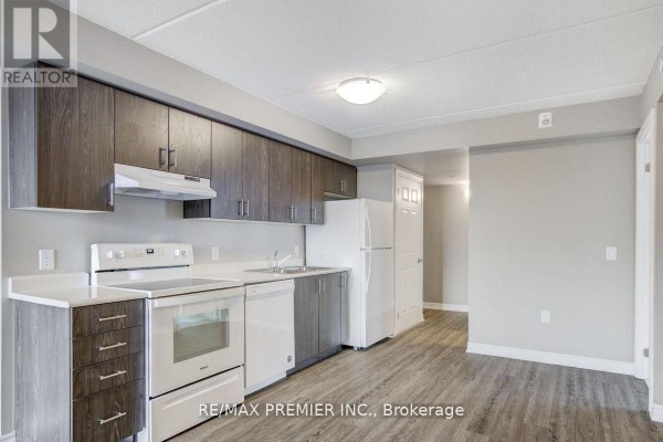 Bedroom with white bi-fold closet doors and view into kitchen with dark cabinets. - 905 - 716 Main Street E, Milton