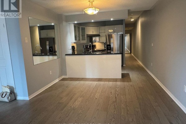 Open concept living area with hardwood floors, view of a kitchen with an island, and a hallway. - 905 - 909 Bay Street, Toronto