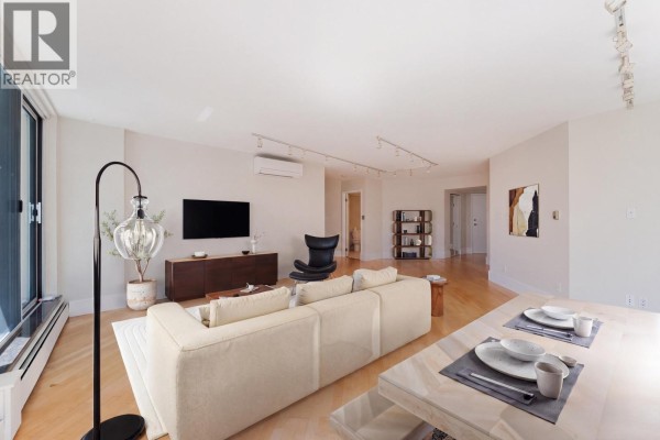 Living room with television, sofa, and view into hallway with doors, next to dining area. - 905 1010 Burnaby Street, Vancouver