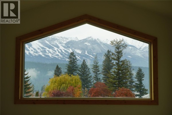 Large geometric window framing a view of snow-capped mountains and trees. - 905 13 Avenue S, Golden
