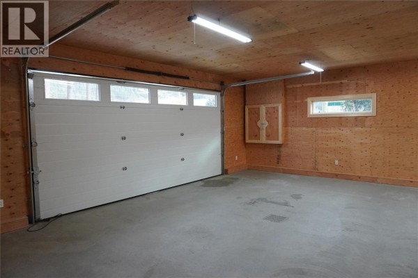 Spacious garage with a white sectional door and wood-paneled walls. - 905 13 Avenue S, Golden
