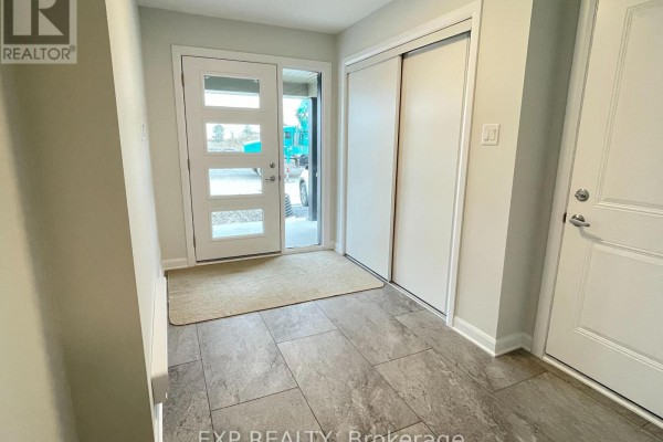 Interior entryway with gray tile flooring, a white closet with sliding doors, and a glass-paneled front door. - 905 Jack Dalgity Street, Mississippi Mills