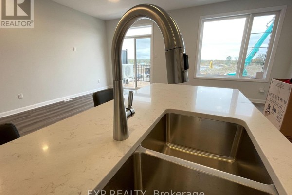Close-up of a kitchen island with a double stainless steel sink and a chrome faucet. - 905 Jack Dalgity Street, Mississippi Mills