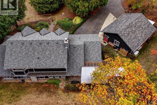 Aerial view of the house and detached garage with surrounding trees. - 905 Worrall Dr, Langford