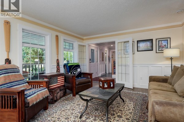 Living room with brown furniture, a patterned rug, wainscoting, and two large wooden oars. - 905 Worrall Dr, Langford
