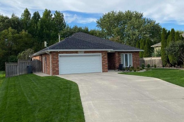 Side view of a brick ranch-style house with a large white garage door and concrete driveway. - 9053 Indian Creek Line E, Chatham Kent