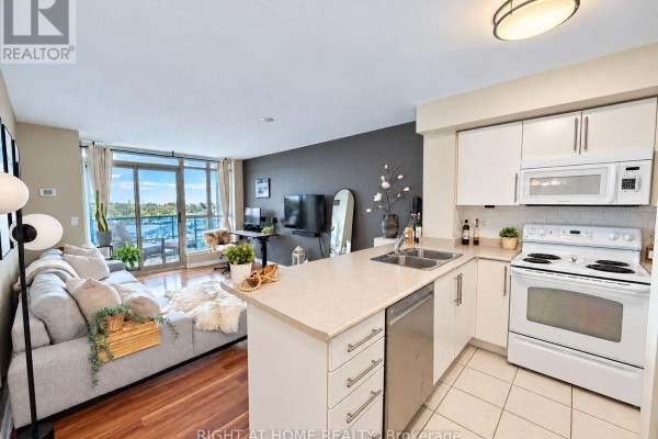 Open concept living area with a kitchen island, sofa, and water view. - 906 - 340 Watson Street W, Whitby