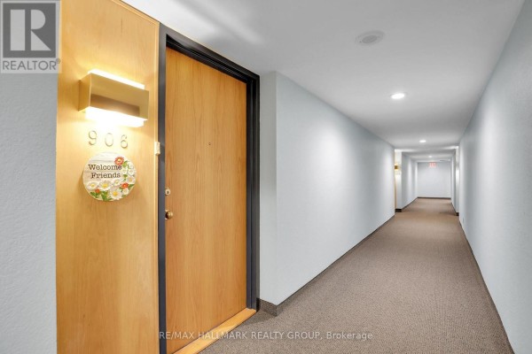 Apartment door 906 with a wooden door and a long, carpeted hallway. - 906 - 960 Teron Road, Ottawa