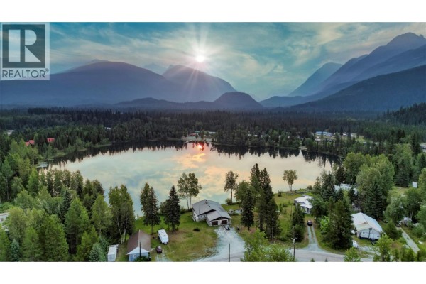 Aerial view of a lake and surrounding forest with mountains in the background at sunset. - 906 Harrwood Drive, Blue River