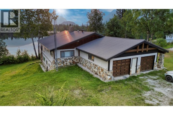 Exterior of a house with stone accents, a large garage, and a sloped lawn. - 906 Harrwood Drive, Blue River