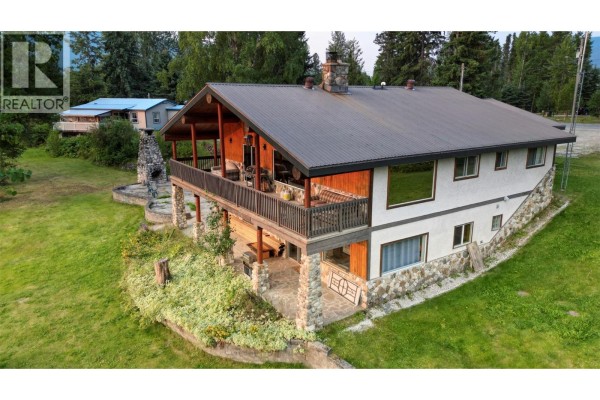 Rear exterior of a multi-level home with a covered deck and stone chimney. - 906 Harrwood Drive, Blue River