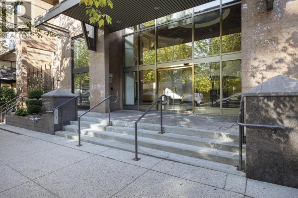 Close-up of the glass entrance to the apartment building with stone pillars and stairs. - 907 1189 Howe Street, Vancouver