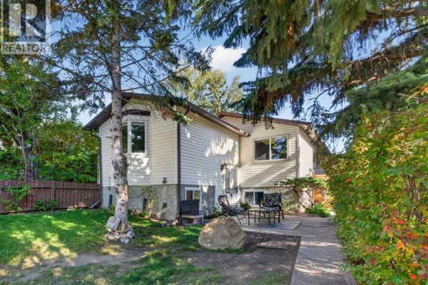 Backyard patio with chairs and a table next to a house with beige siding. - 907 Ranchview Crescent Nw, Calgary