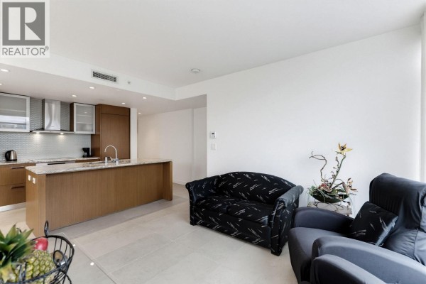 Open concept kitchen with island and modern appliances, next to seating area with sofa. - 908 1028 Barclay Street, Vancouver