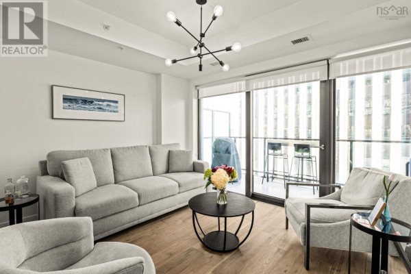 Living room with gray sofa, round coffee table, and large glass doors to the balcony. - 908 1650 Granville St, Halifax