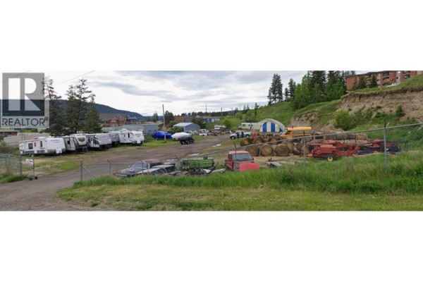 View of the property showcasing parked vehicles, trailers, and storage items on the land. - 908 Proctor Street, Williams Lake