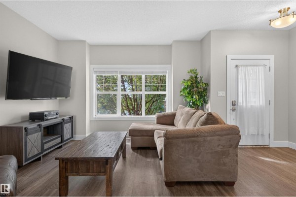 Living room with a large sectional sofa, coffee table, and television on a stand. - 9082 Rosenthal Link Li Nw, Edmonton