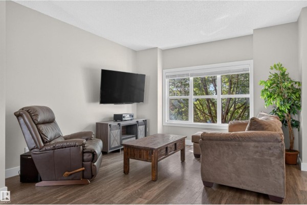 Living room featuring a brown leather recliner, sectional sofa, coffee table, and television. - 9082 Rosenthal Link Li Nw, Edmonton