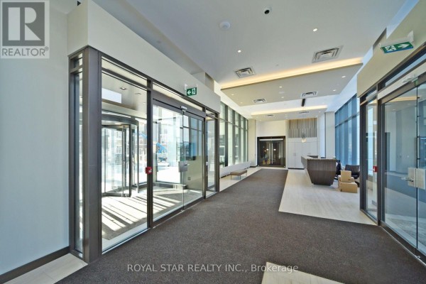 Bright, modern lobby with glass doors, carpeted floor, and reception desk. - 909 - 10 Honeycrisp Crescent, Vaughan