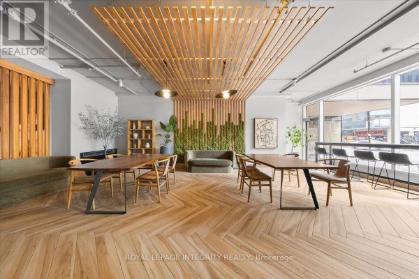 Building lobby with fireplace, seating area, herringbone wood floors, and a grand staircase with glass railings. - 909 - 161 Laurier Avenue W, Ottawa