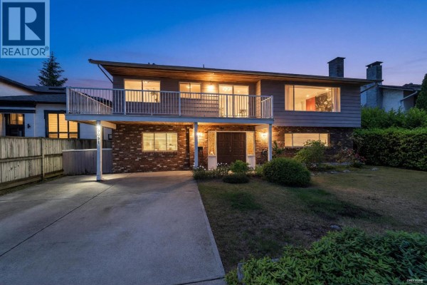 Rear view of the house at dusk with a large backyard and white exterior. - 9091 Ash Street, Richmond