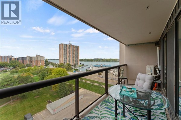 Apartment entryway with a refrigerator, wooden door, mirrored closet, and tiled floor. - 9099 Riverside Drive East Unit# 907, Windsor
