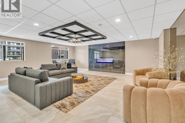 Lounge area with beige and grey sofas, a gold coffee table, a fireplace, and mirrored walls. - 9099 Riverside Unit# 402, Windsor