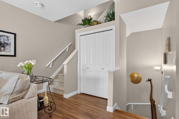 Living room entrance with light beige walls, wood flooring, and a white bi-fold door. - #91 7293 South Terwillegar Dr Nw, Edmonton