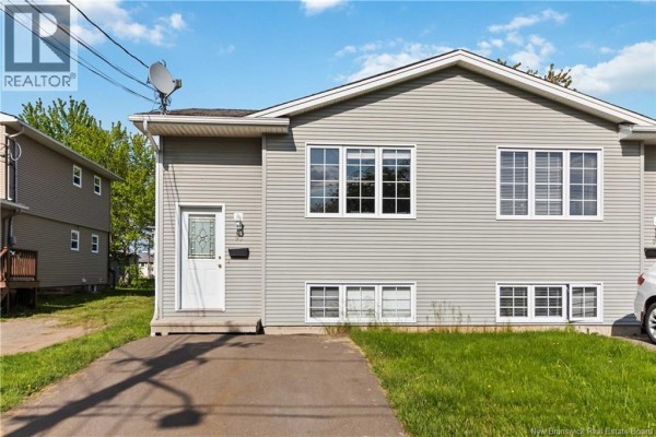 Side view of a duplex with beige vinyl siding, showing one entrance door and windows on both levels. - 91-93 Second Avenue, Moncton