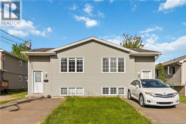 Front exterior of a duplex with a white SUV parked in the driveway on the right side. - 91-93 Second Avenue, Moncton