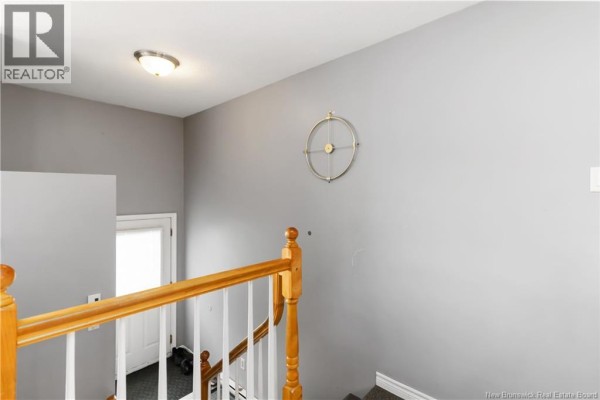 Interior view of a hallway with grey walls, a wooden banister, and a white door at the end. - 91-93 Second Avenue, Moncton