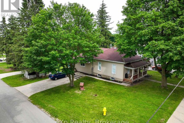 Aerial view of the light yellow house with a long driveway and mature trees surrounding the property. - 91 Charles Street, North Huron